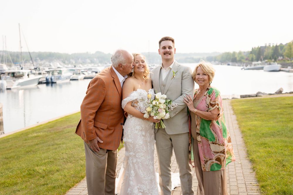 A group of people pose together outdoors with a scenic marina and mountains in the background.