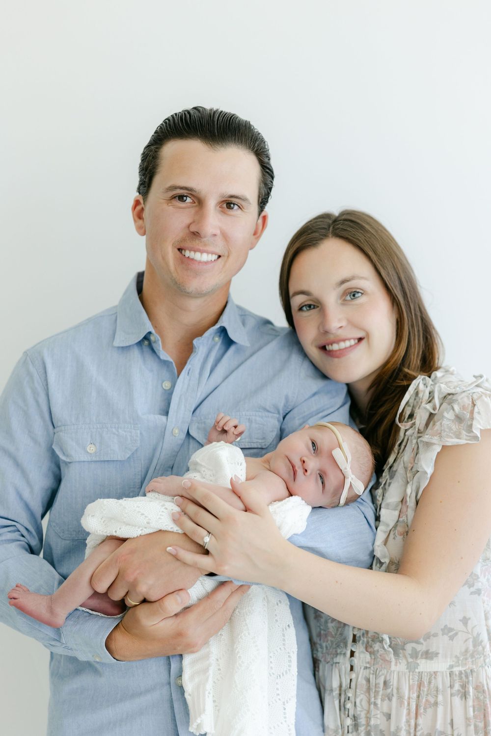 A couple in blue and white outfits holds their newborn baby in a series of tender portraits.