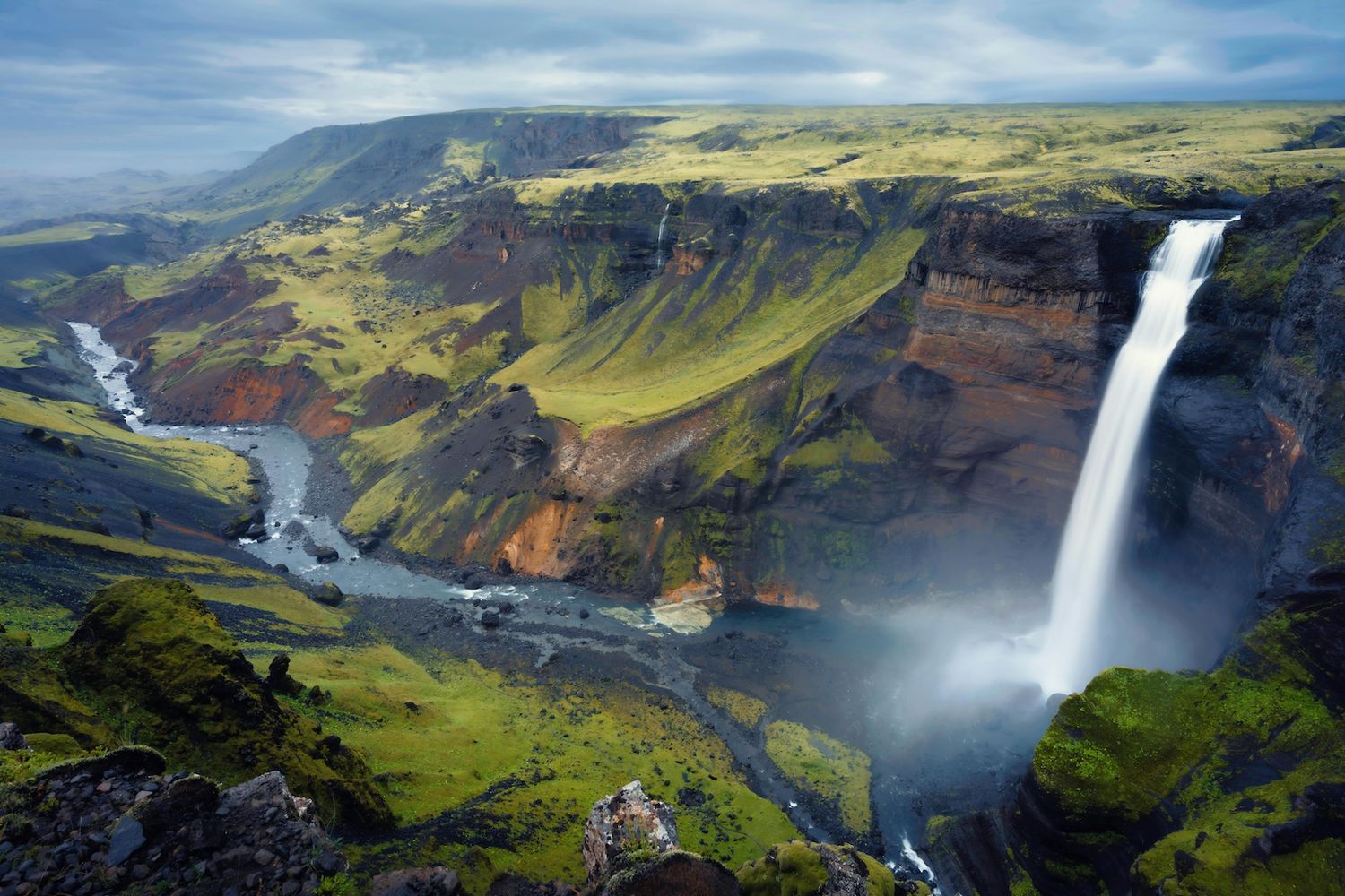 Waterfall surrounded by lush green mountains in Iceland