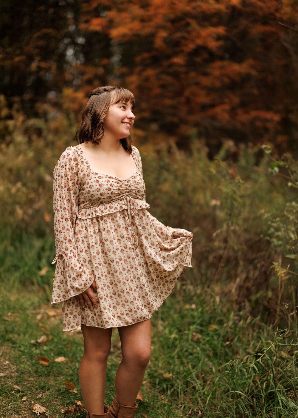 A vintage-inspired floral dress captured in a field with warm autumn colors in the background.
