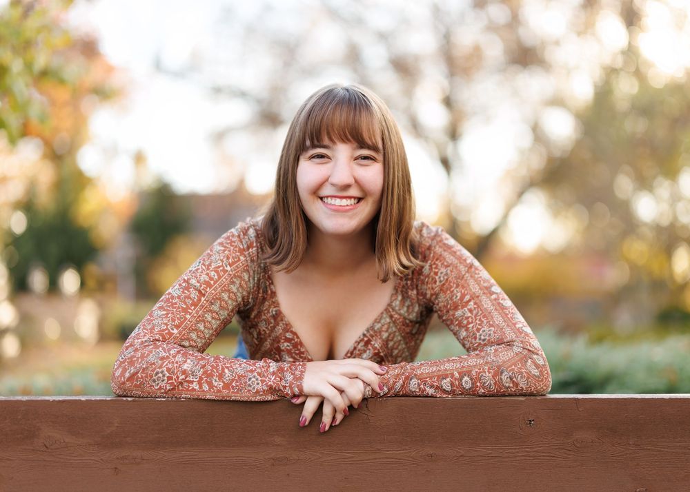 A wooden railing provides a natural prop for outdoor portrait photography.