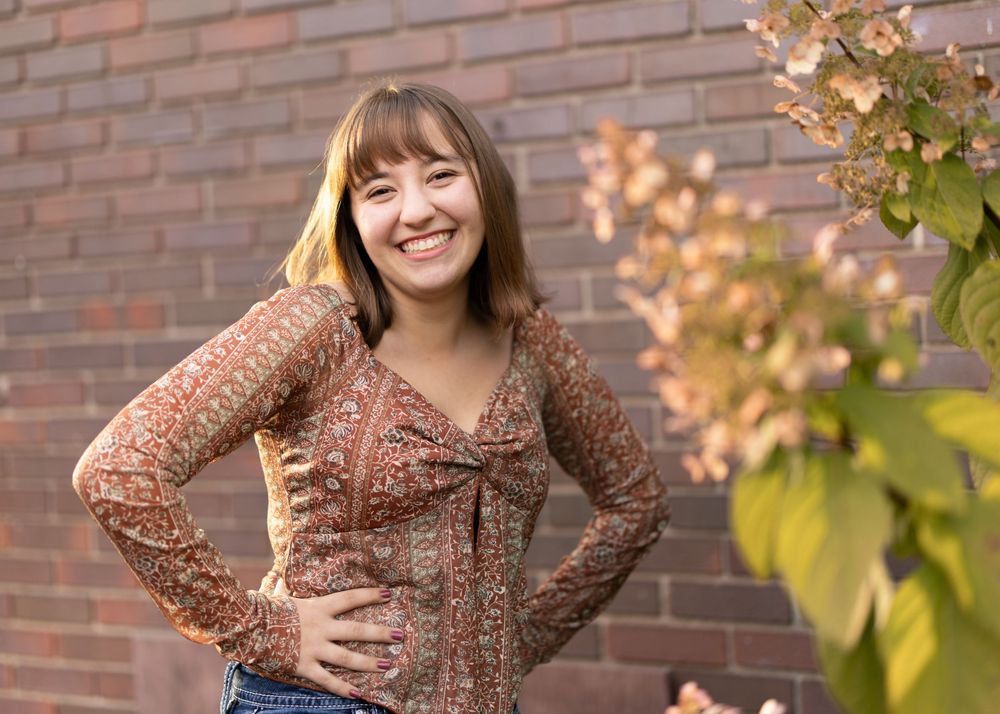A floral print top photographed against a rustic brick wall with autumn foliage.