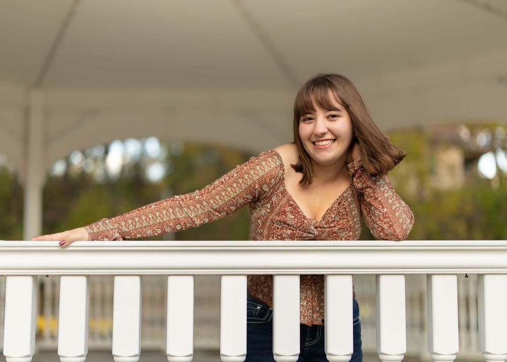 White porch columns create an architectural frame for a casual outdoor portrait setting.