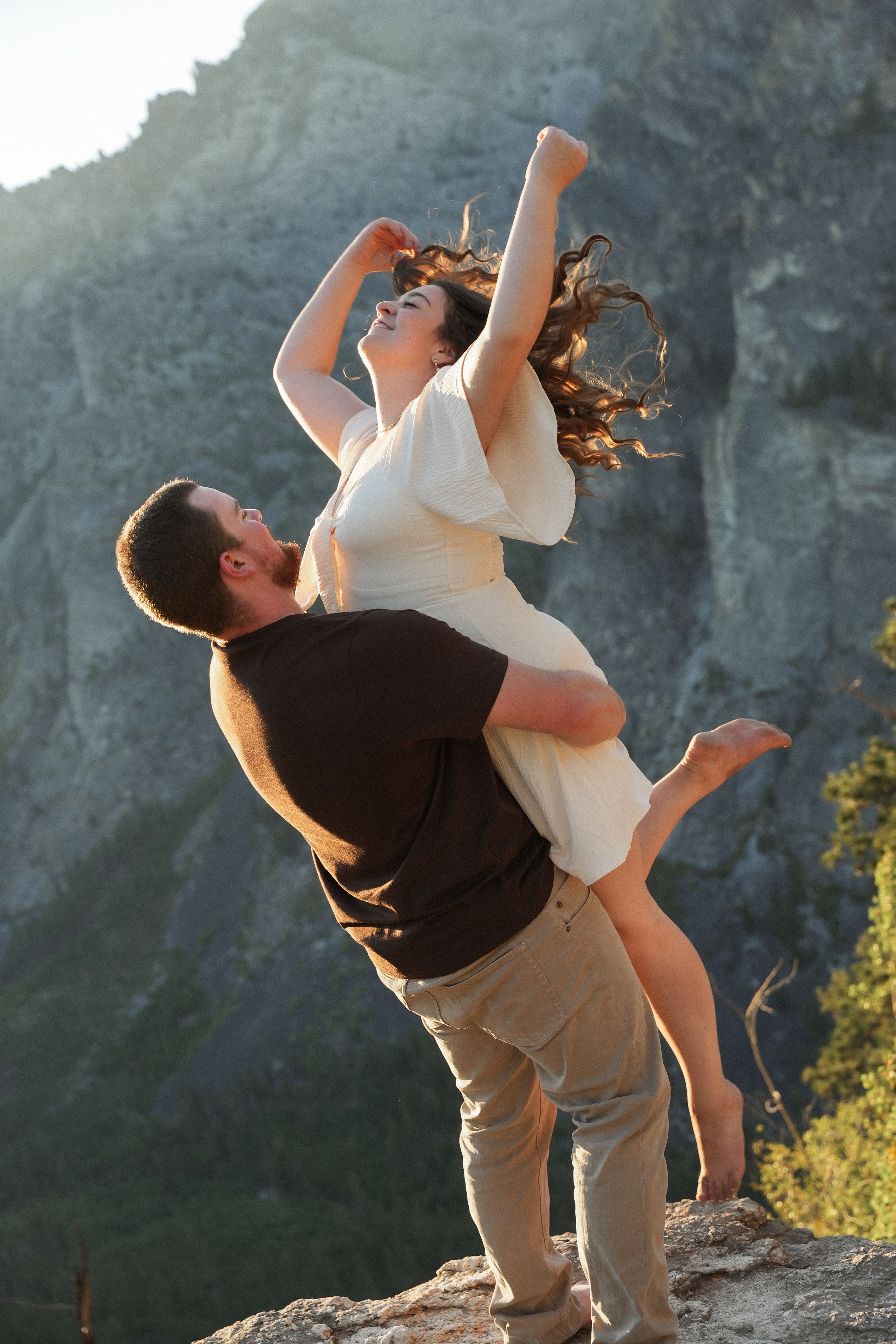Two dancers perform a dramatic lift sequence against a mountainous backdrop at sunset.