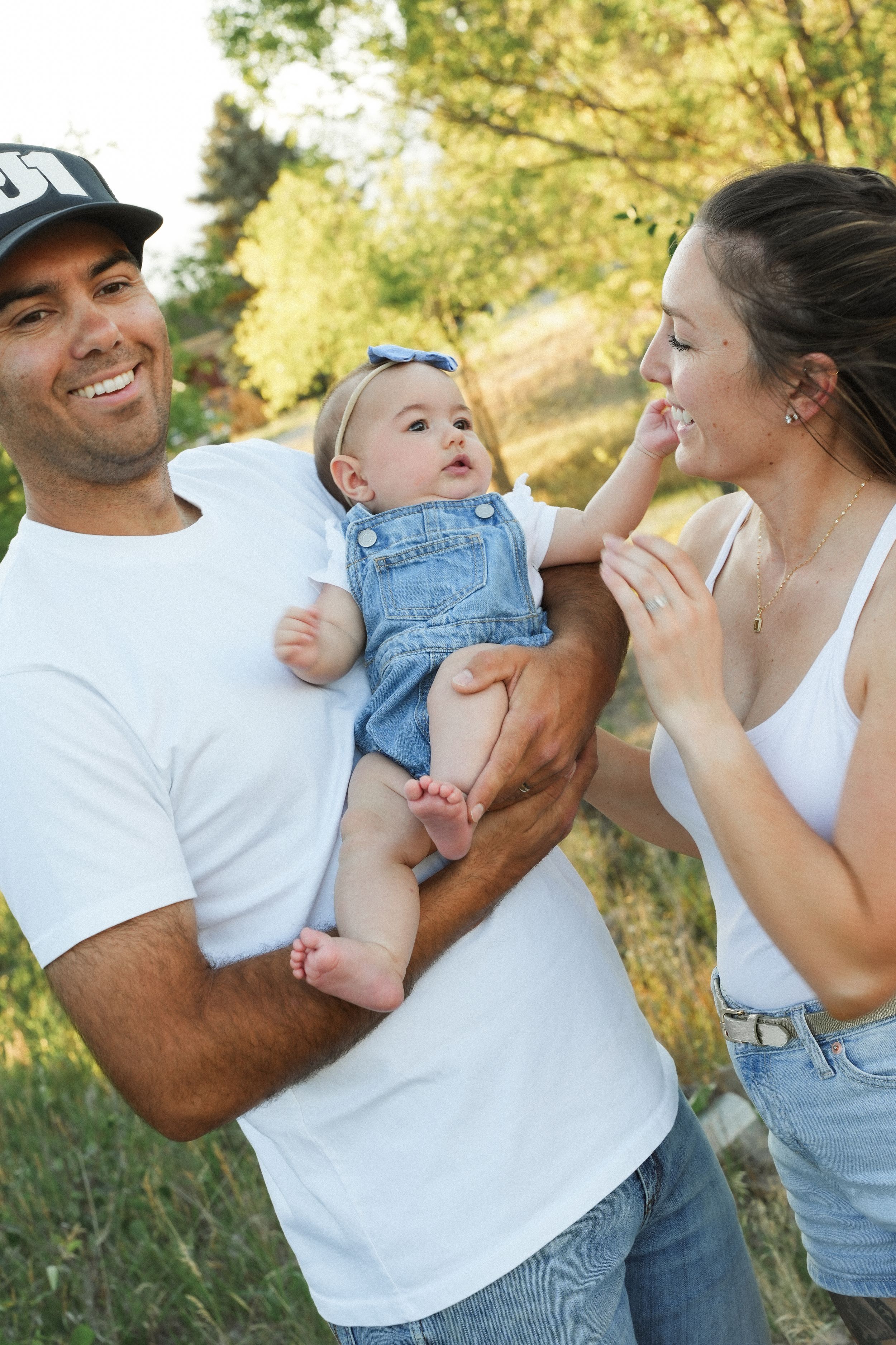 Couple in white shirts and denim share playful candid moments outdoors during a photo session.