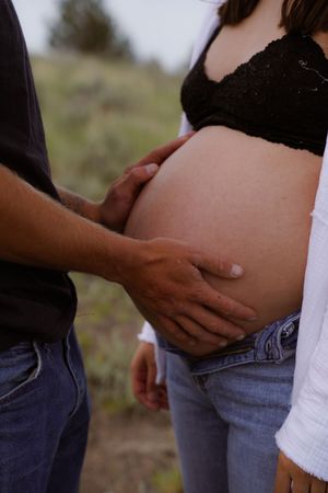 A sequence of hands gently cradling a pregnant belly wearing blue jeans and white shirt.