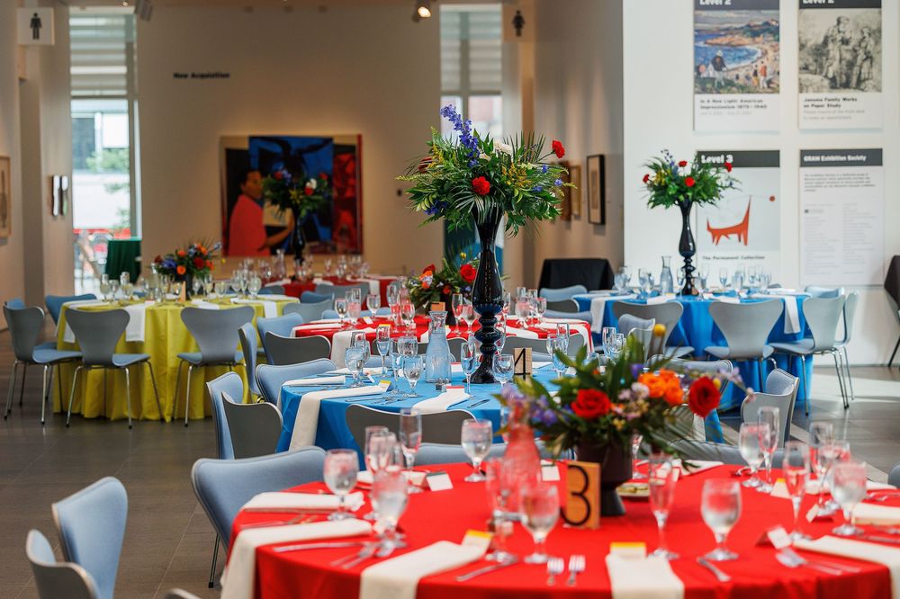 Banquet hall set up with round tables decorated in red and blue tablecloths for a formal event.