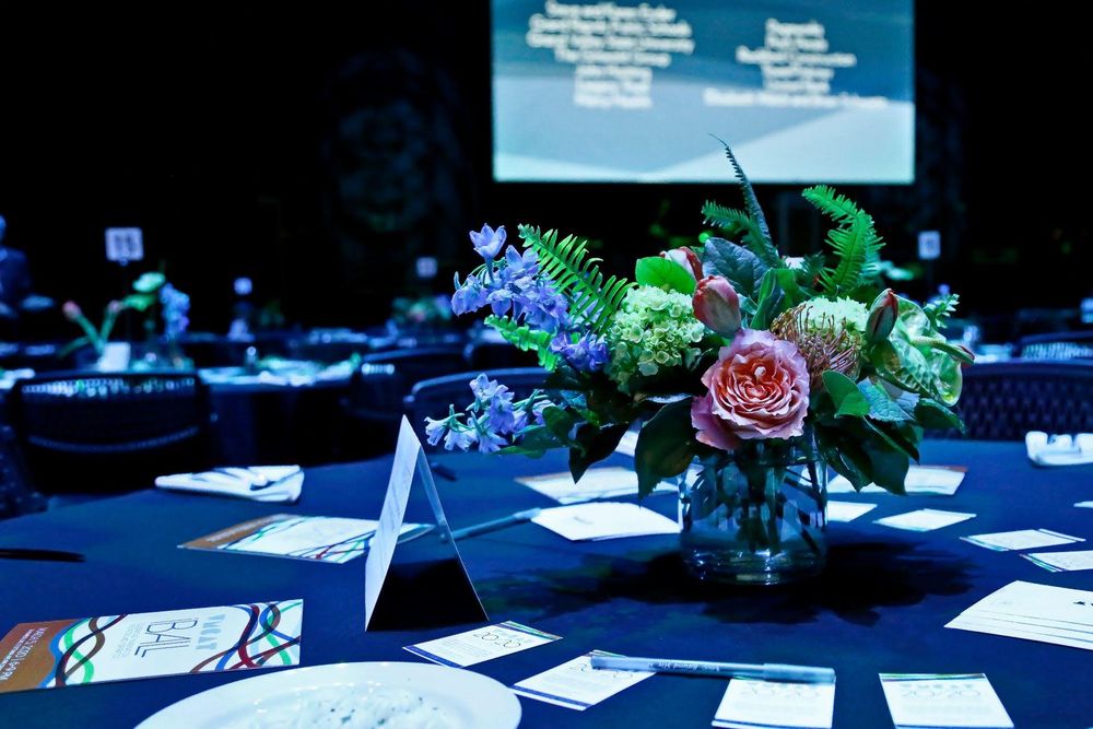 Corporate event tables decorated with blue lighting and floral centerpieces in a professional setting.