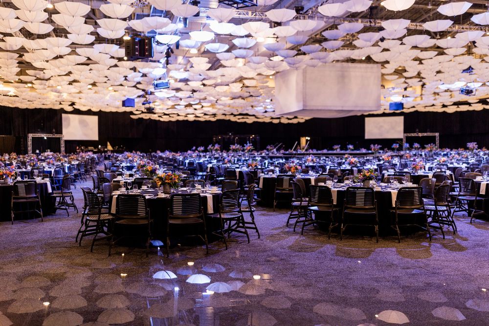 Large banquet hall with round tables and blue uplighting on the ceiling creates an elegant atmosphere for an event.