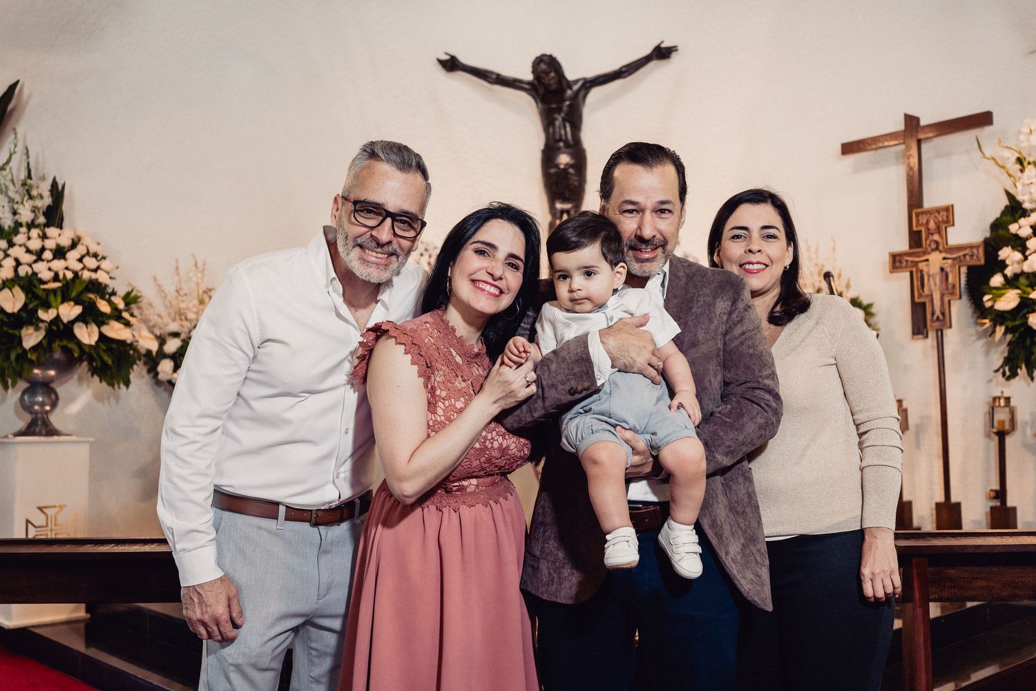 A group of people pose together in a church setting with crosses and religious decor visible in the background.