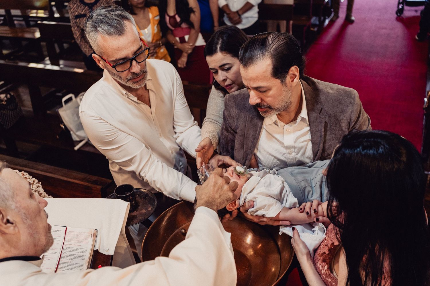 Wedding guests laugh and enjoy themselves during a lively reception celebration at an indoor venue.