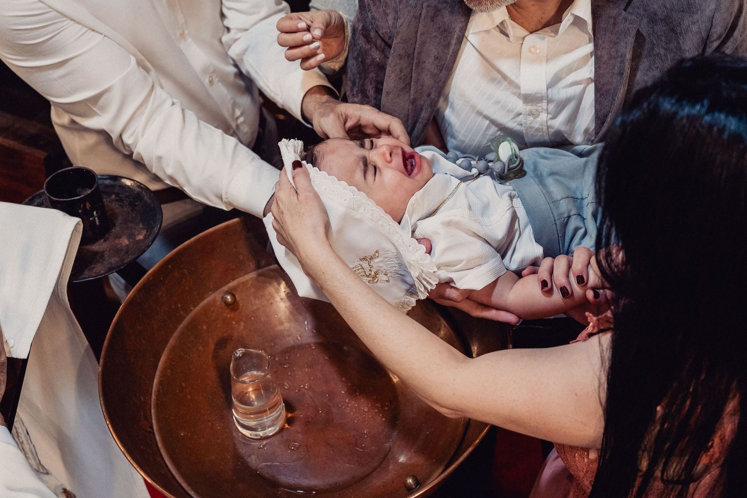 A close-up shot of hands pouring champagne into multiple glasses on a rustic wooden tray.