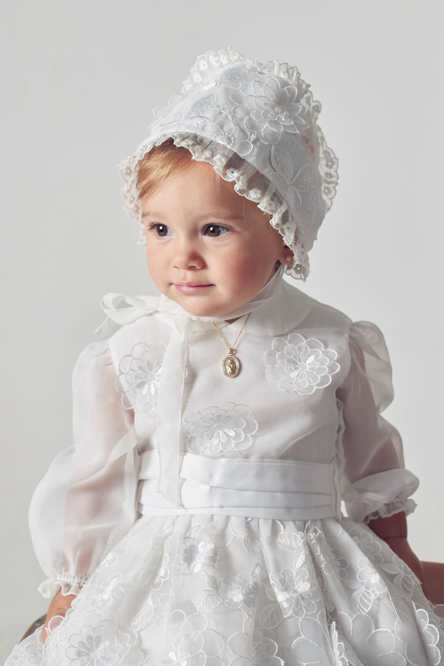Beautiful white christening gown with delicate lace details and matching bonnet for a special baptism ceremony.