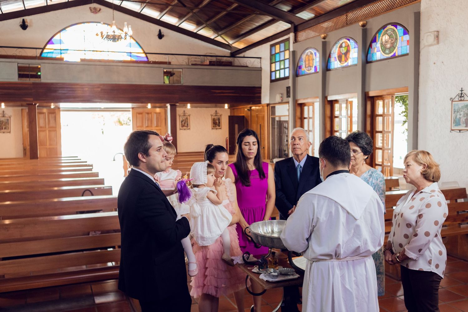 Wedding guests gathered inside a rustic wooden church with stained glass windows for a ceremony.