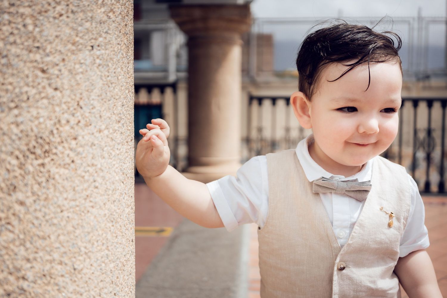 A child in formal white attire smiling during a special occasion indoors.