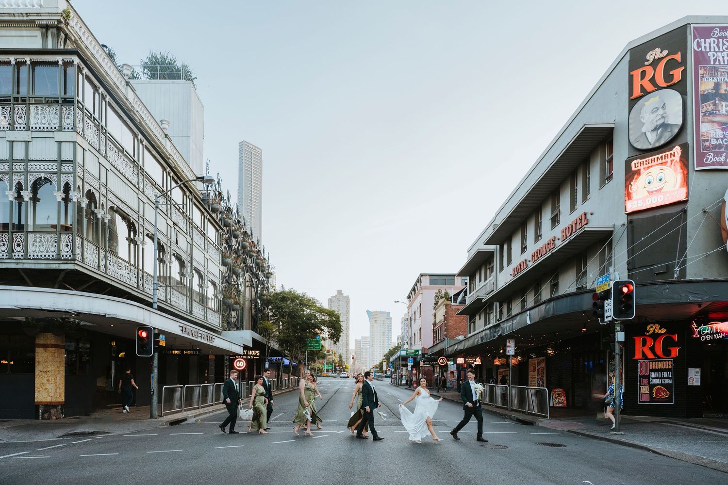 People crossing a street intersection in downtown Perth, Australia with urban buildings and storefronts visible.