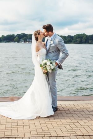 A romantic lakeside wedding photo sequence showing a couple in white dress and gray suit embracing by the water.