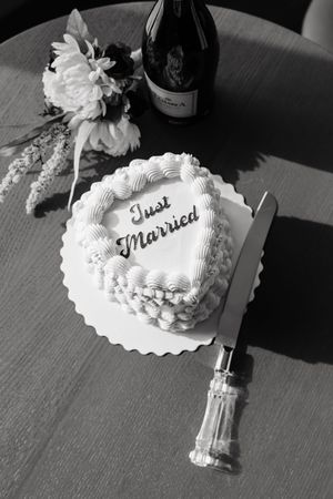 A series of black and white photos showing a white wedding cake decorated with frosting and 'Just Married' text on top.