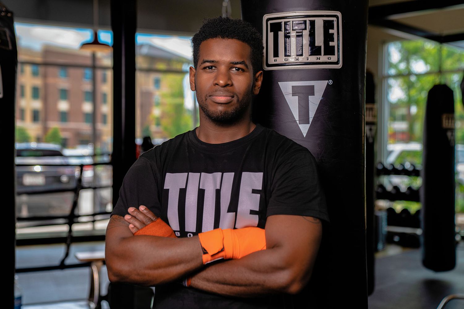 Fitness athlete standing with arms crossed in front of gym equipment at Title Boxing Gym in Summerville South Carolina