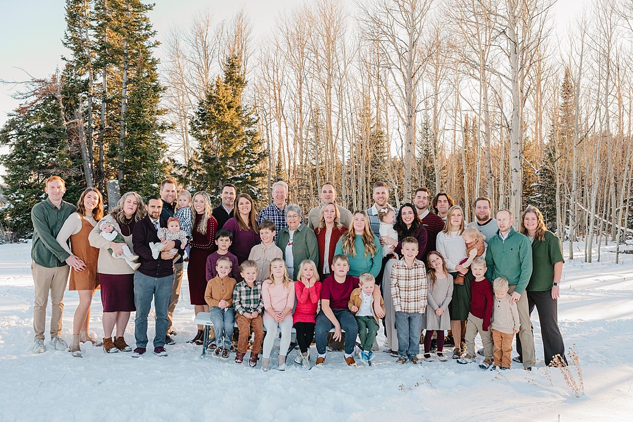Large group poses together in snowy winter setting with bare trees and evergreens in background.