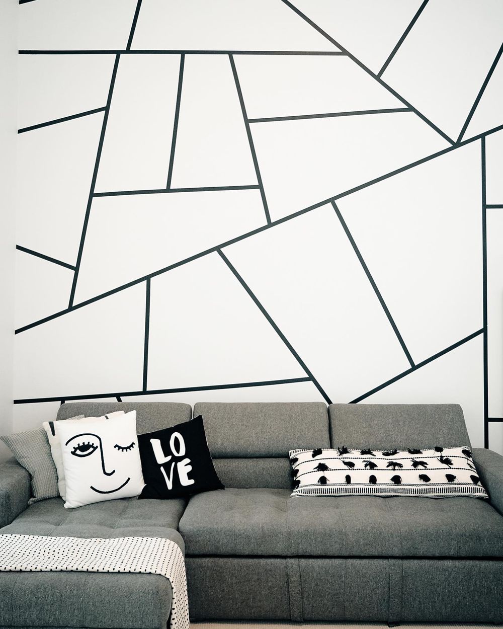 Decorative throw pillows with minimalist face designs arranged on a modern gray sofa in a monochromatic living room.