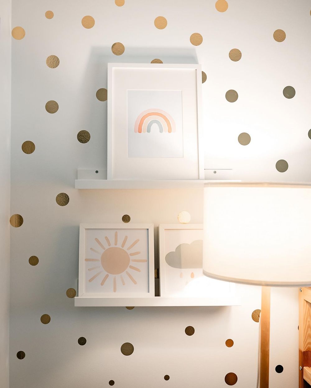 White wall decorated with gold polka dot decals and simple framed artwork featuring minimalist sun and rainbow designs.