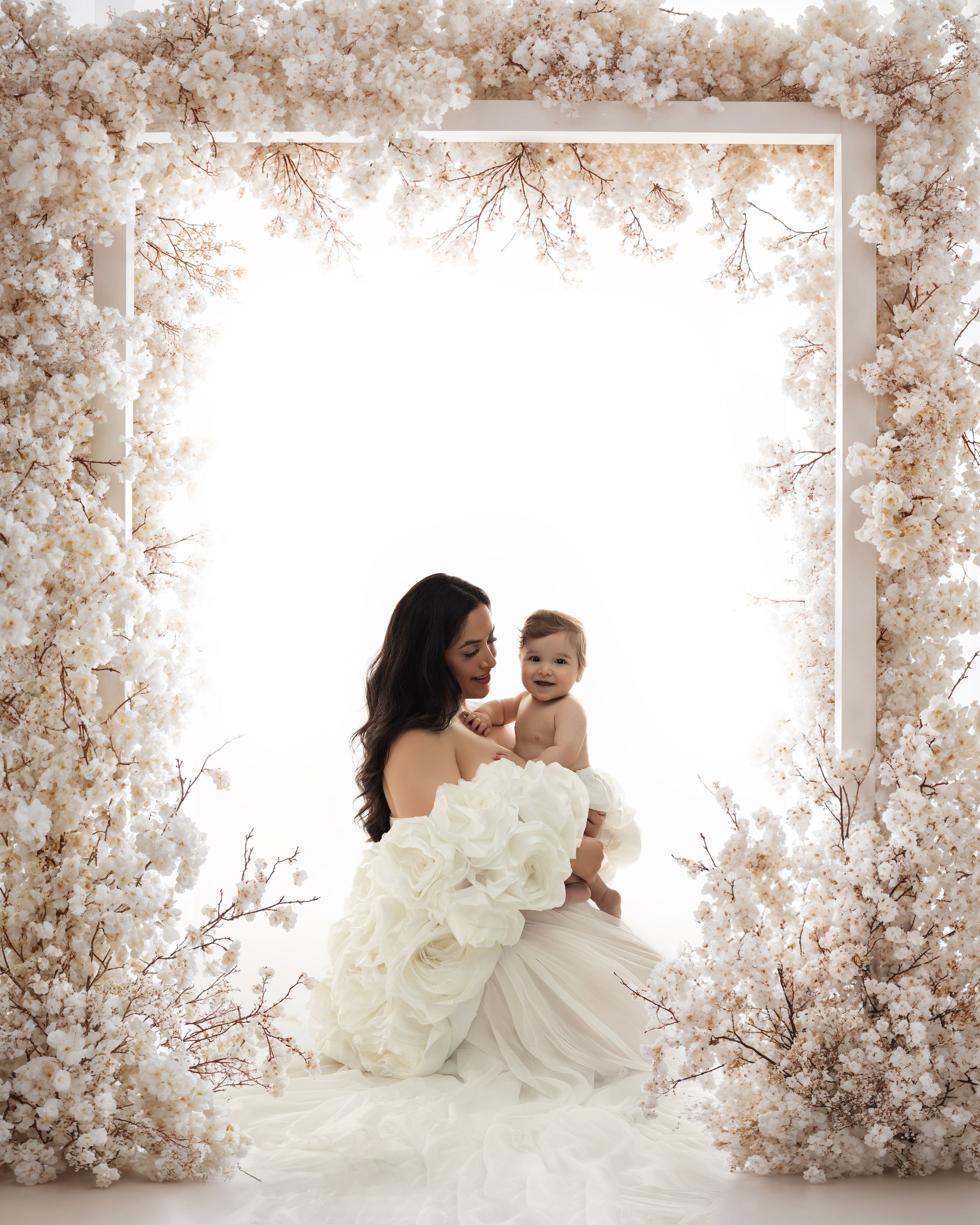 A dreamy romantic portrait series set against a backdrop of delicate white and blush cherry blossoms in a studio setting.