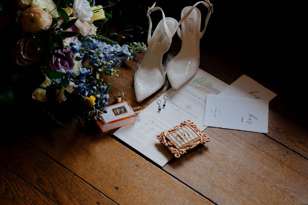 Writing supplies and floral arrangements sit on a rustic wooden table during a wedding preparation.