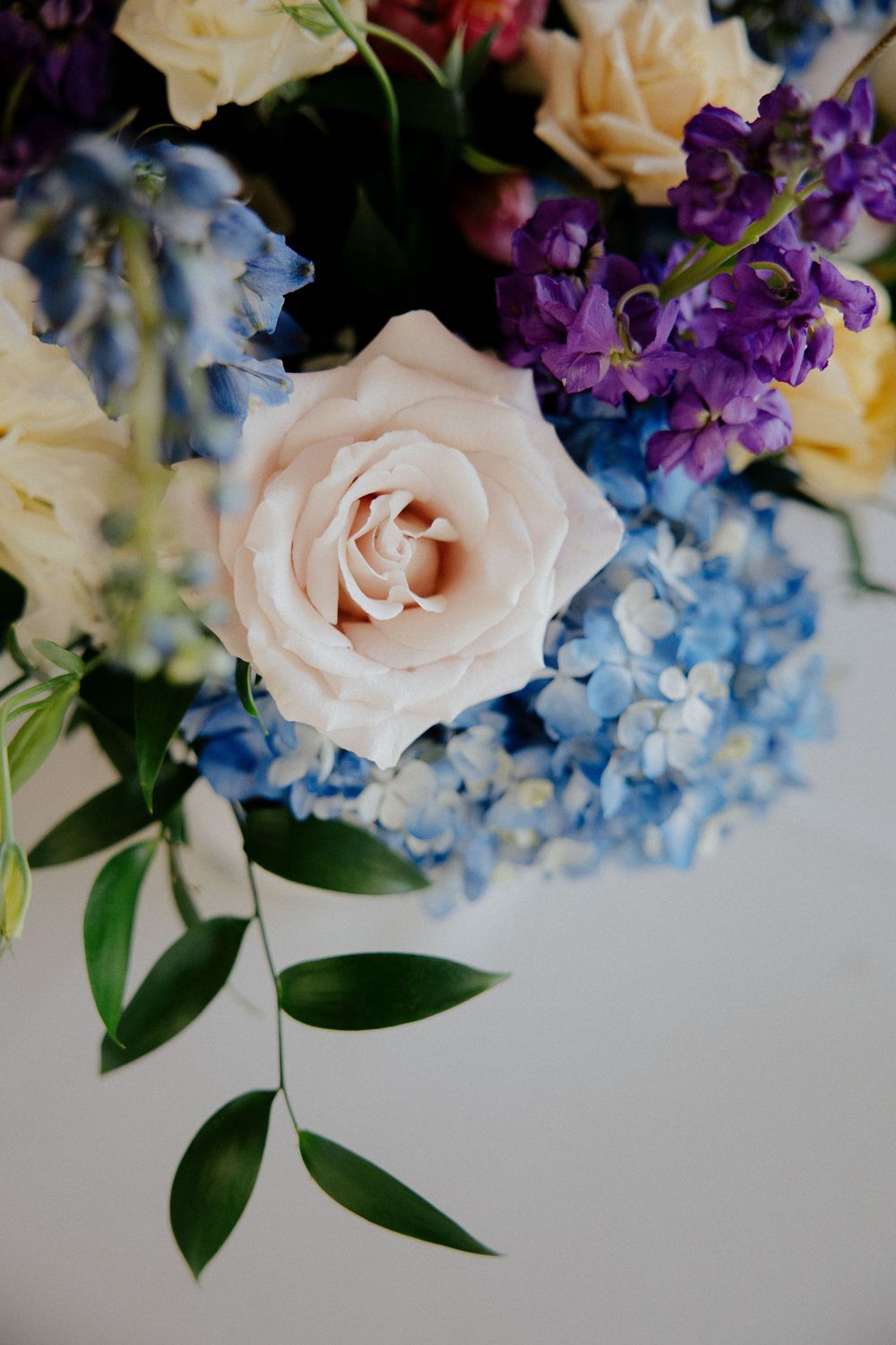 Close-up of pastel floral arrangement featuring roses, hydrangeas and purple blooms.