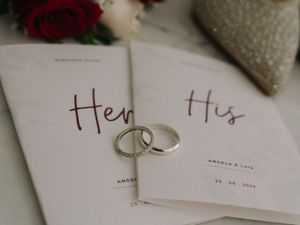 His and Hers wedding vow books with two silver rings, roses, and names Angela and Luis dated 28.08.2024.