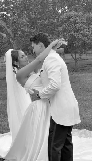 Black and white photo of a bride and groom embracing outdoors, sharing a romantic dance on their wedding day.