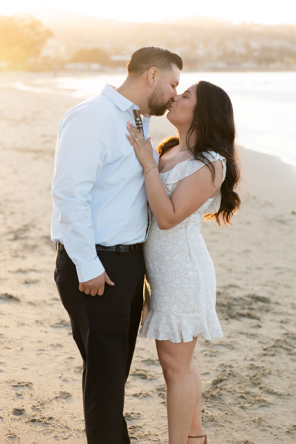A romantic beach photoshoot at sunset with a couple in white and black attire.