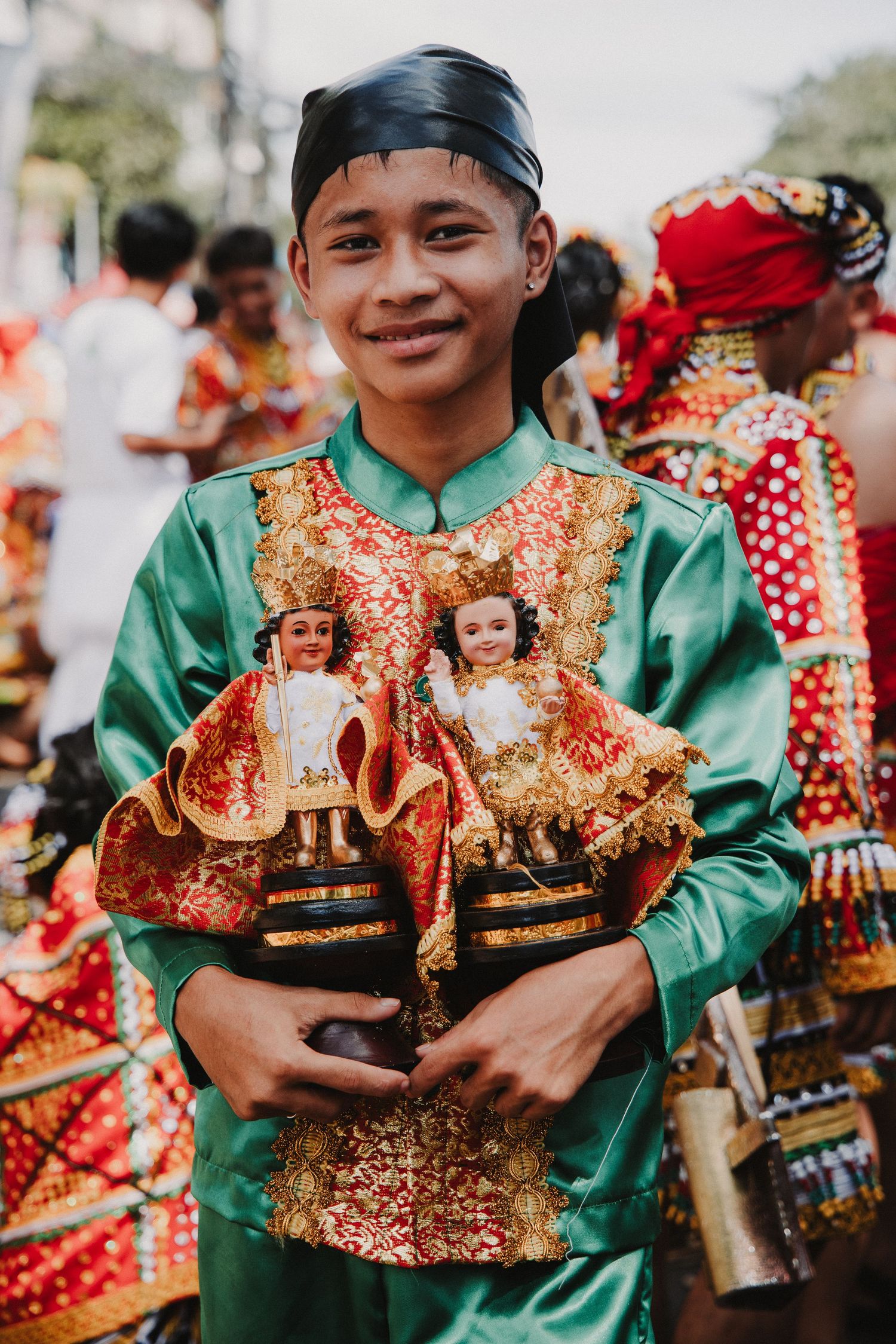 Young performers in green shirts holding decorative religious icons during a cultural festival.