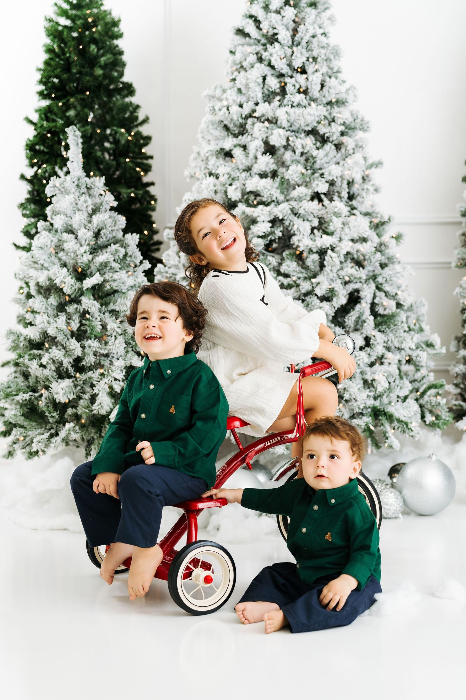 Children with vintage red tricycle prop in Christmas photo setup in Houston Texas