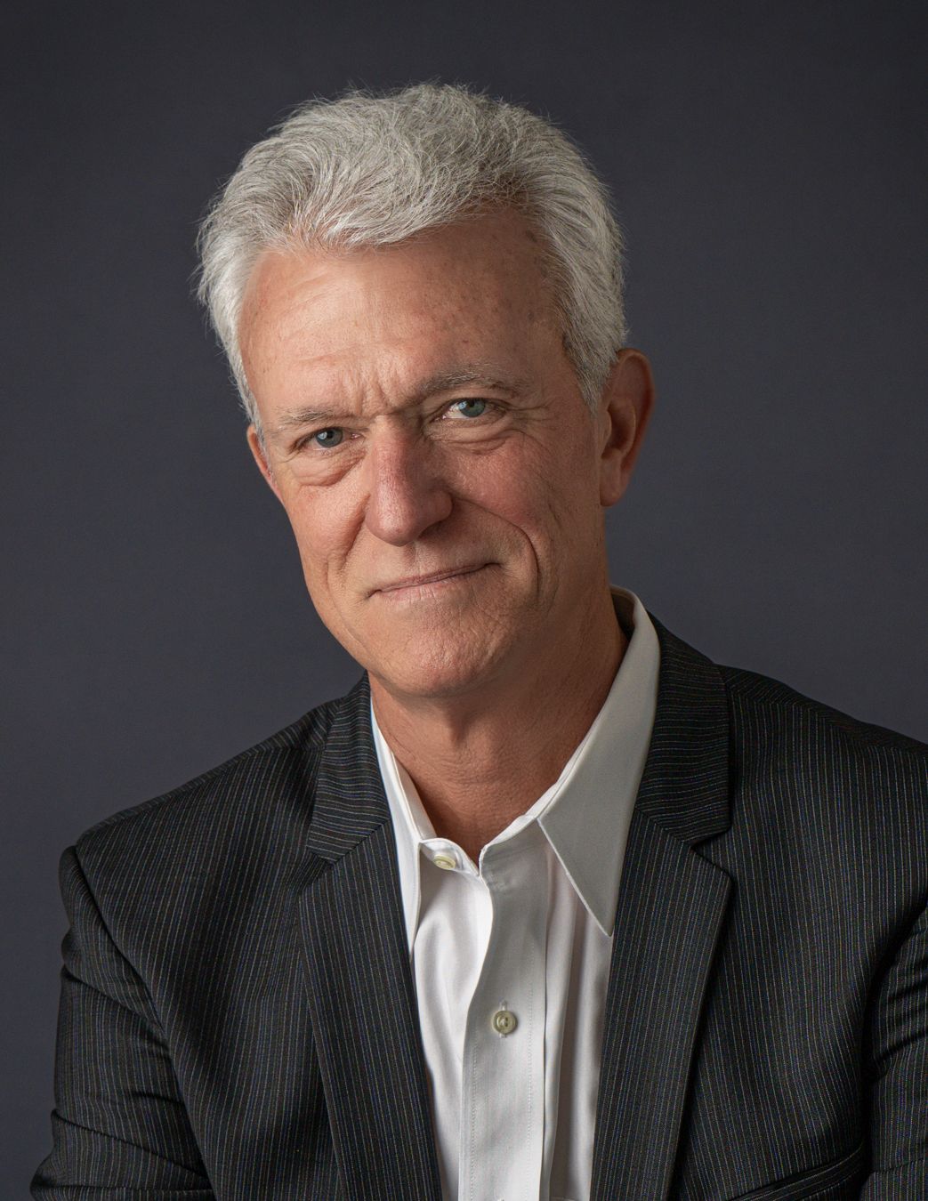 Professional headshot of a senior man with gray hair in a dark blazer.