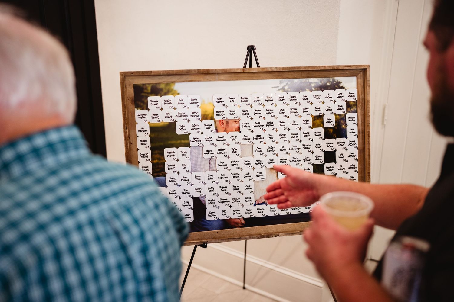 Person assembling a periodic table display using individual element cards on a wall.