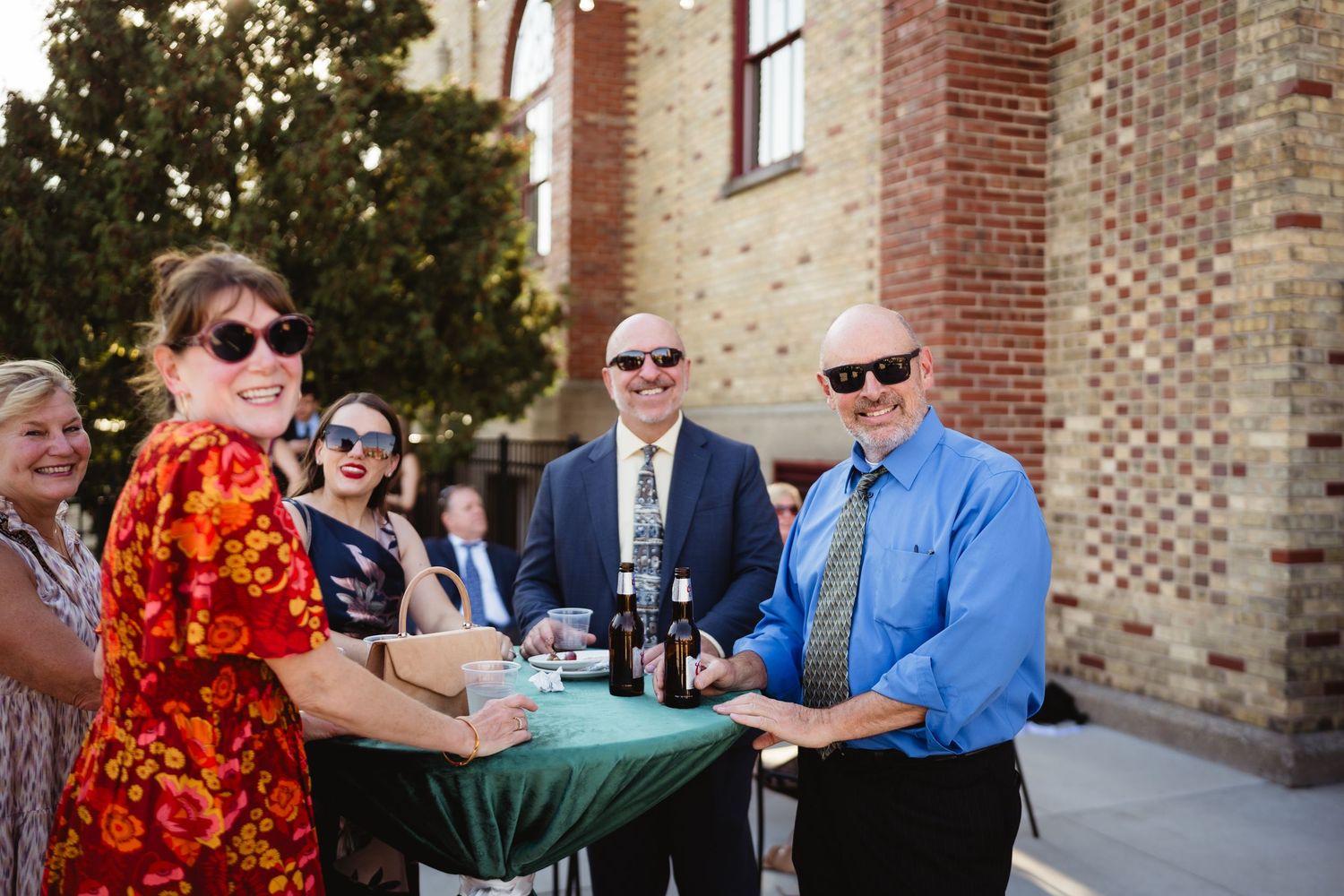 A series of outdoor wedding celebration photos showing guests dancing and socializing at a brick venue.