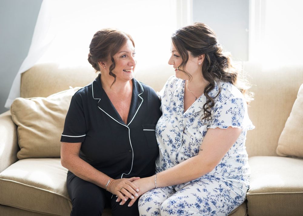 Two people sit together on a couch, sharing a warm conversation and laughter in a bright, sunlit room.
