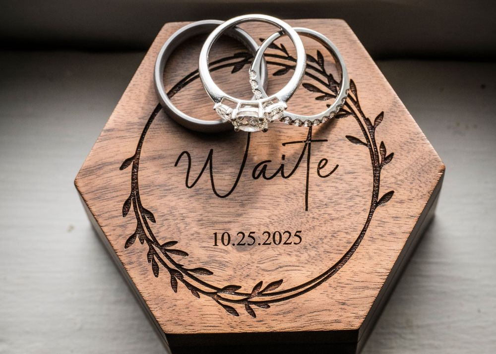 Wooden hexagonal ring holder with custom name and date engraving for wedding ceremony.