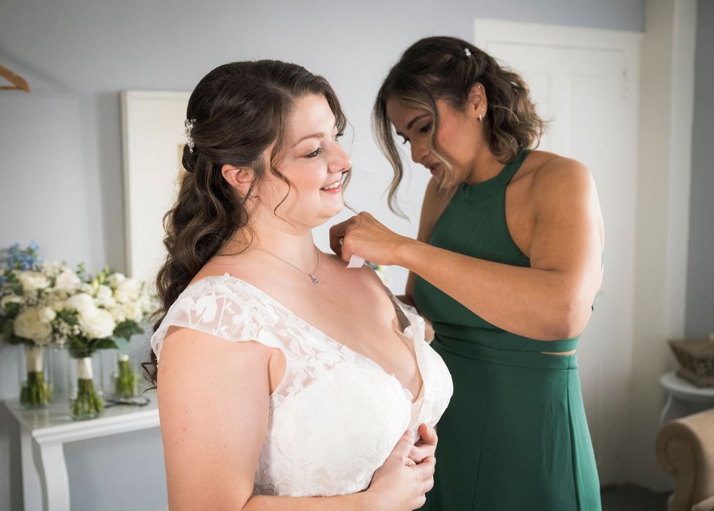 Two women in white and green dresses share a joyful moment together during a wedding celebration.