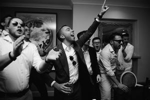 Black and white photo showing a lively party scene with people celebrating and dancing in an indoor venue.