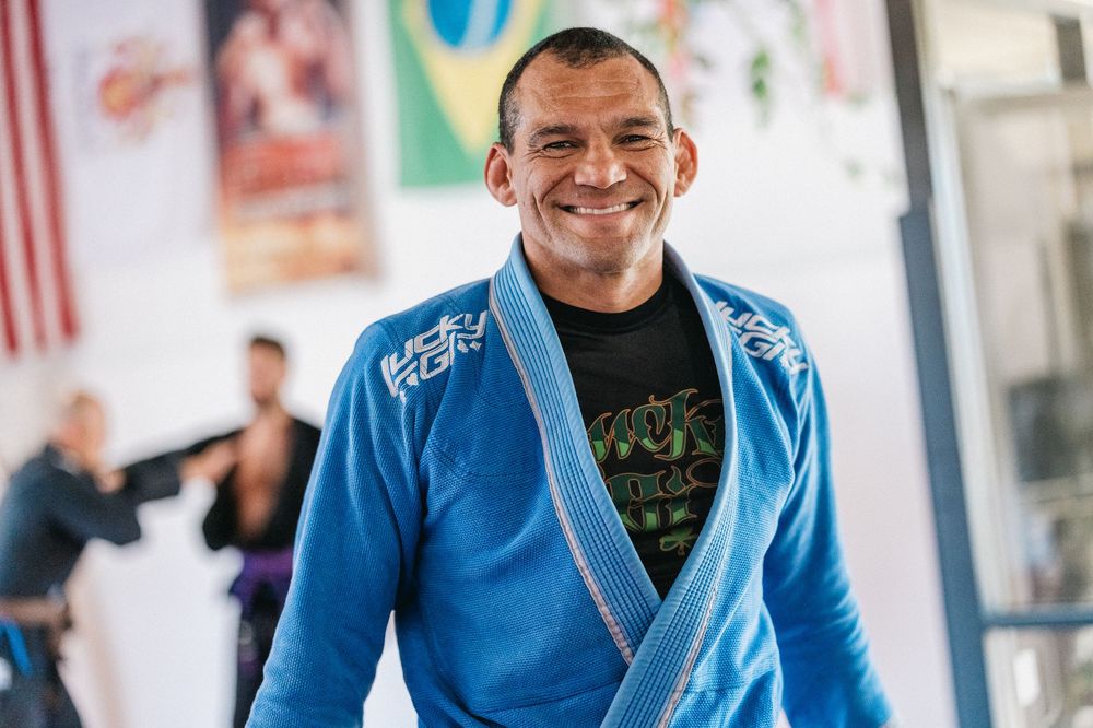 Students practicing Brazilian jiu-jitsu moves in a bright training facility with blue mats.