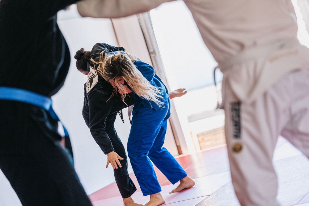 Two martial artists practicing self-defense techniques in a bright training studio.