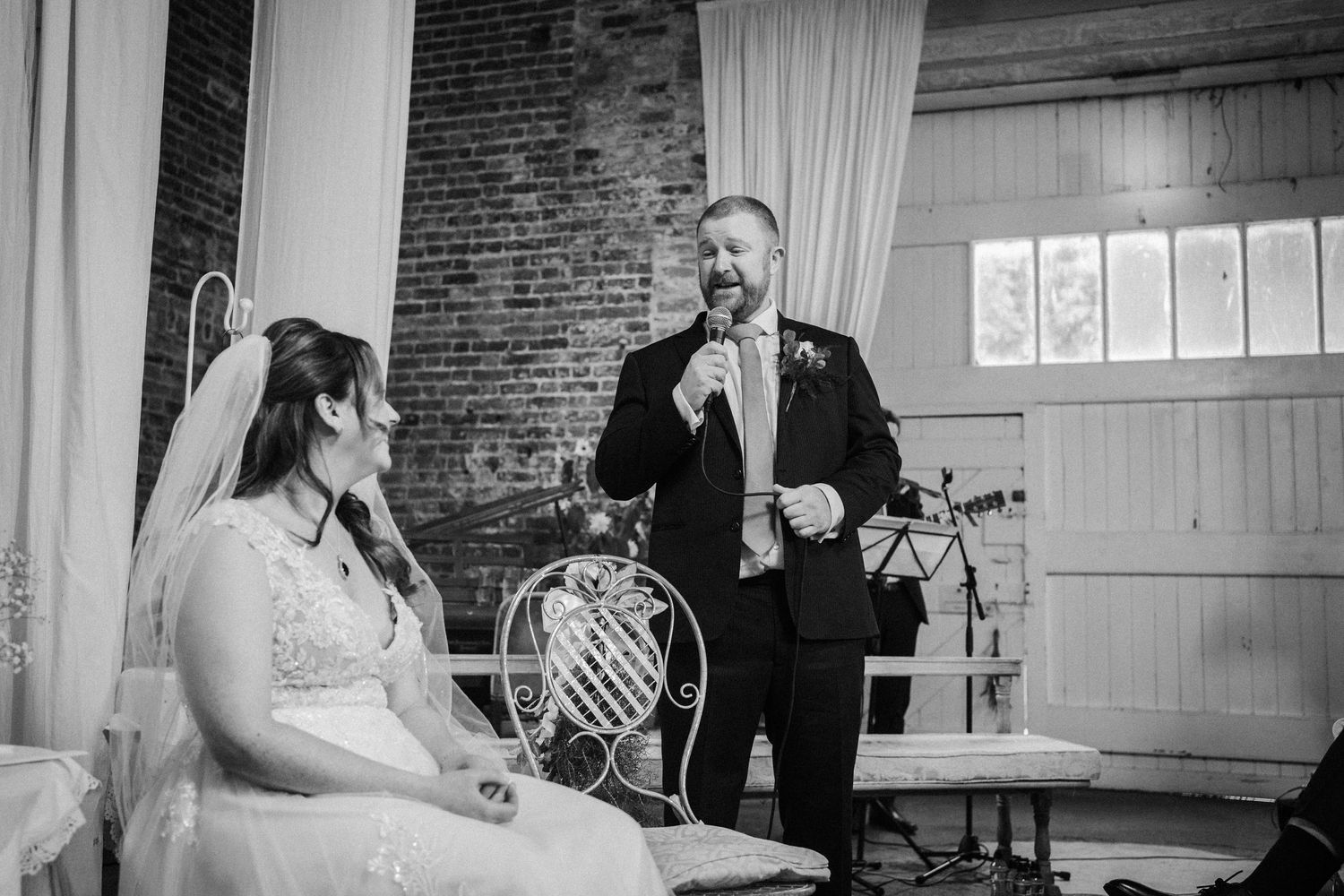 Black and white photo showing wedding guests seated at tables during a reception celebration.