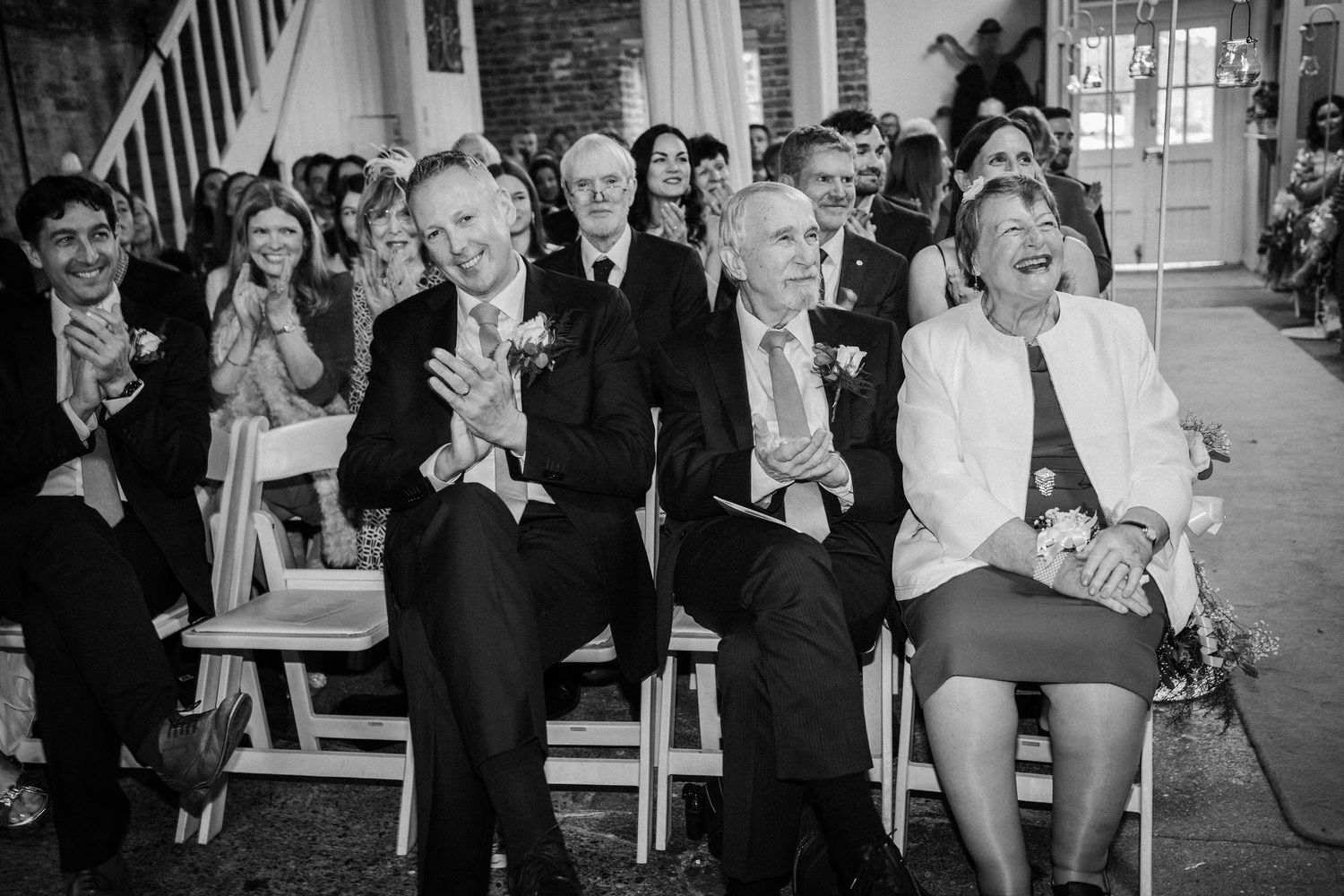Wedding guests react with joy and laughter during an emotional ceremony moment.