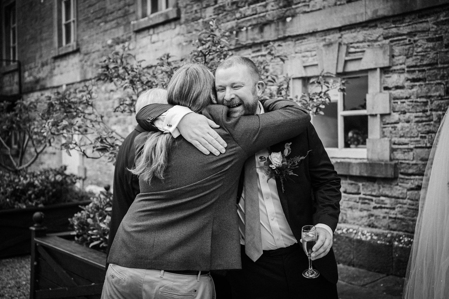 Black and white photos show emotional embraces against a stone building wall.