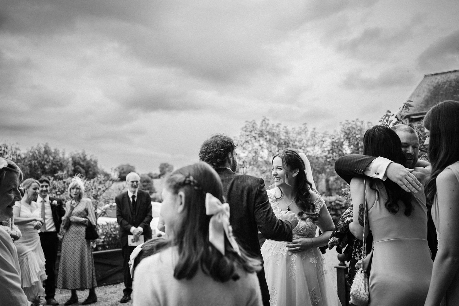 Wedding guests gather outdoors at a scenic venue celebrating during a cloudy afternoon celebration.