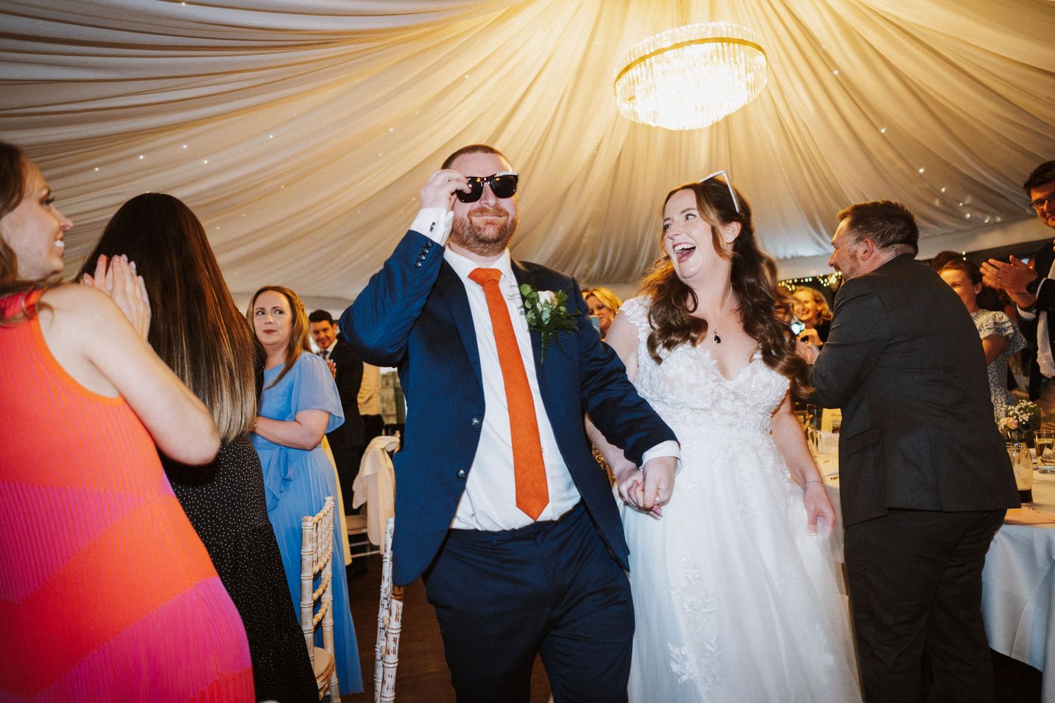 Wedding guests dance and celebrate together on a dimly lit dance floor at an elegant reception venue.
