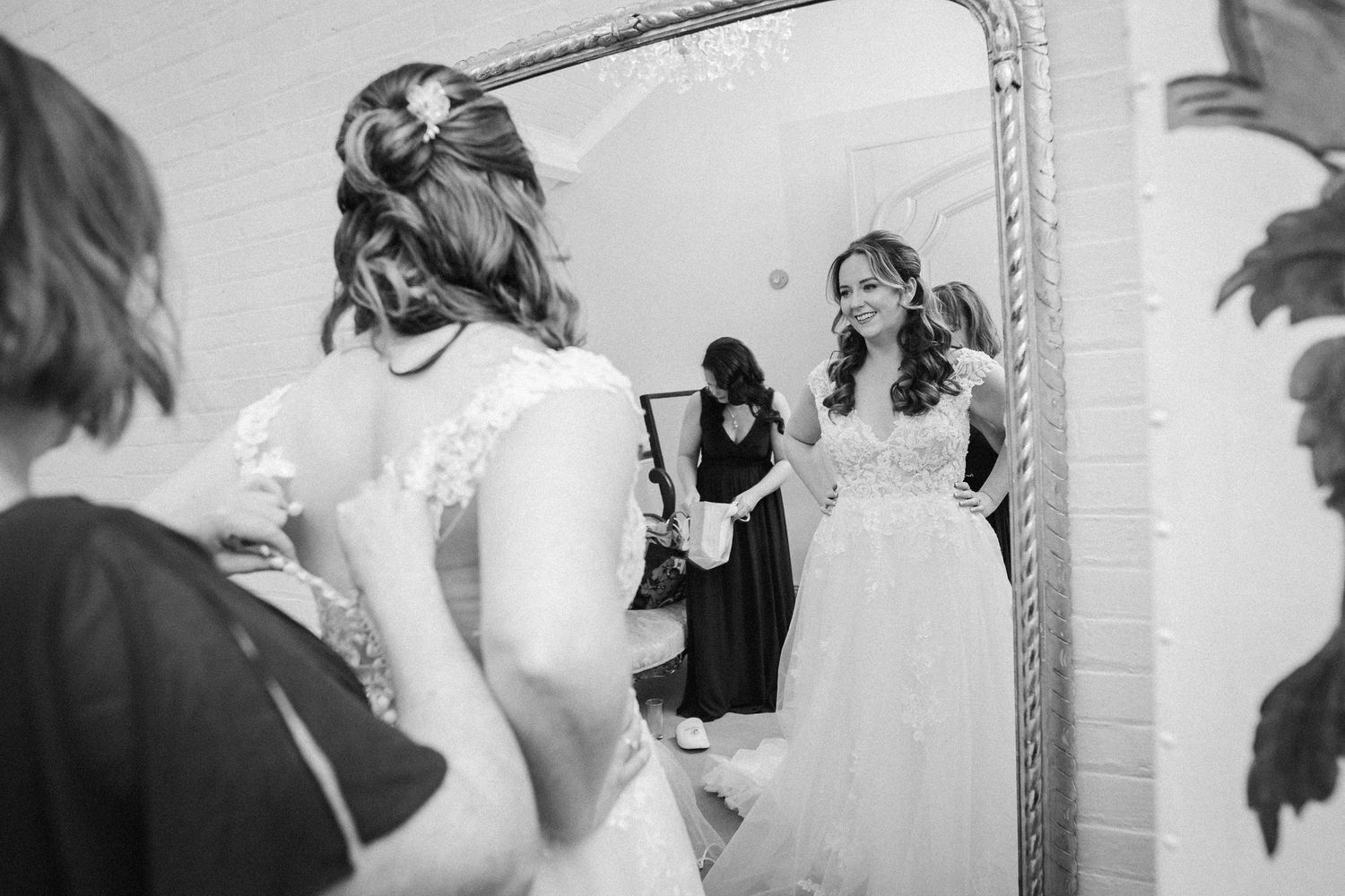 A series of black and white wedding preparation photos showing details of getting ready in a bridal suite.