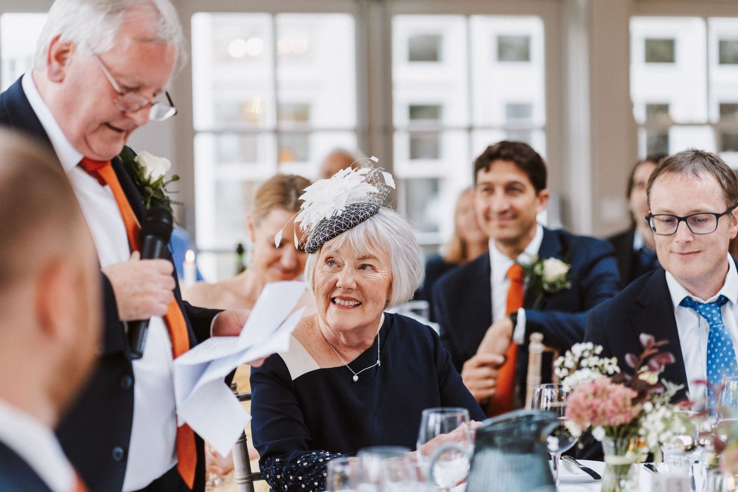 Wedding reception guests enjoy conversations and laughter during an indoor celebration.